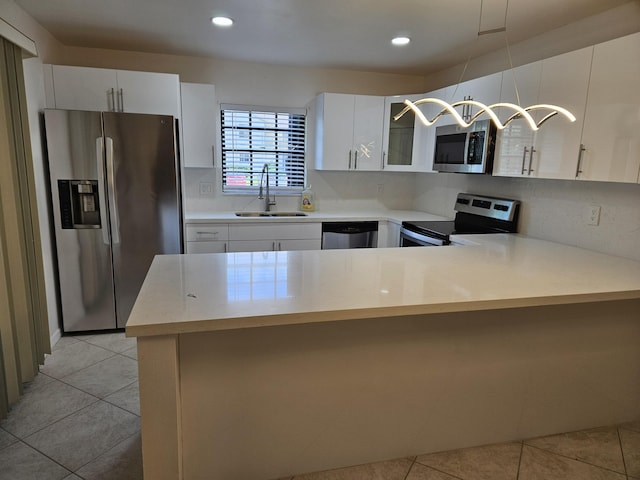 kitchen featuring light tile patterned floors, stainless steel appliances, a peninsula, a sink, and light countertops