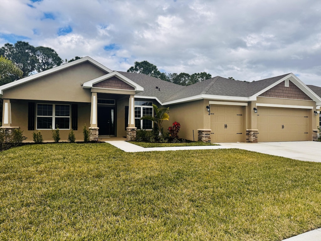 craftsman inspired home with a front lawn, an attached garage, and stucco siding