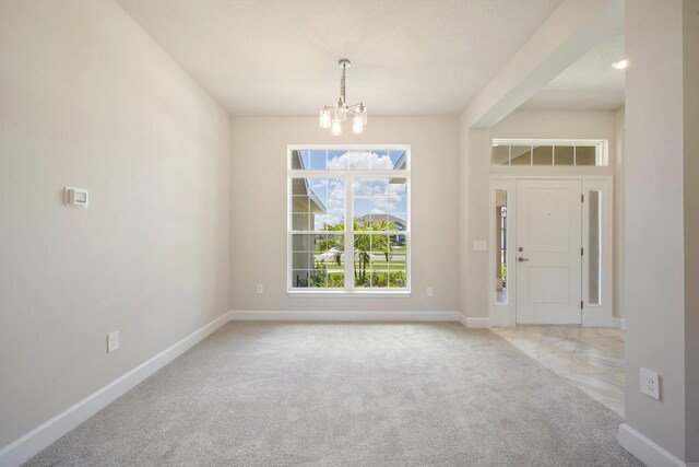 carpeted foyer featuring an inviting chandelier