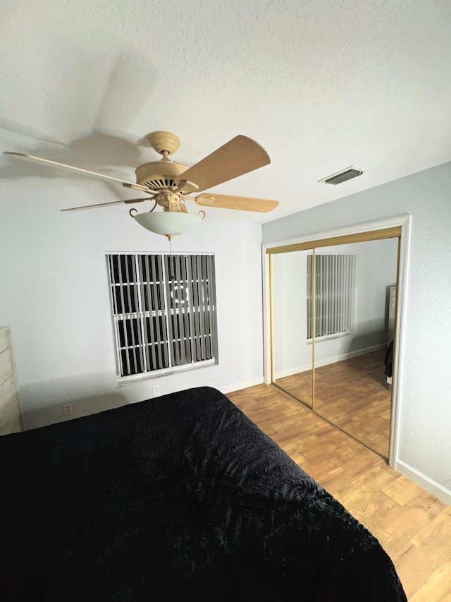 unfurnished bedroom with light hardwood / wood-style floors, ceiling fan, a closet, and a textured ceiling