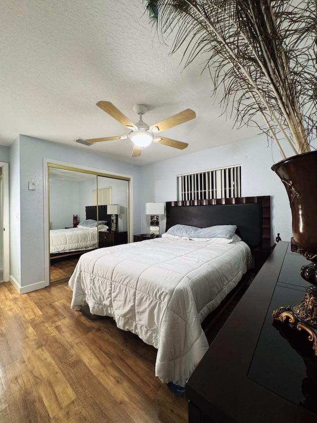 bedroom with a textured ceiling, a closet, ceiling fan, and wood-type flooring