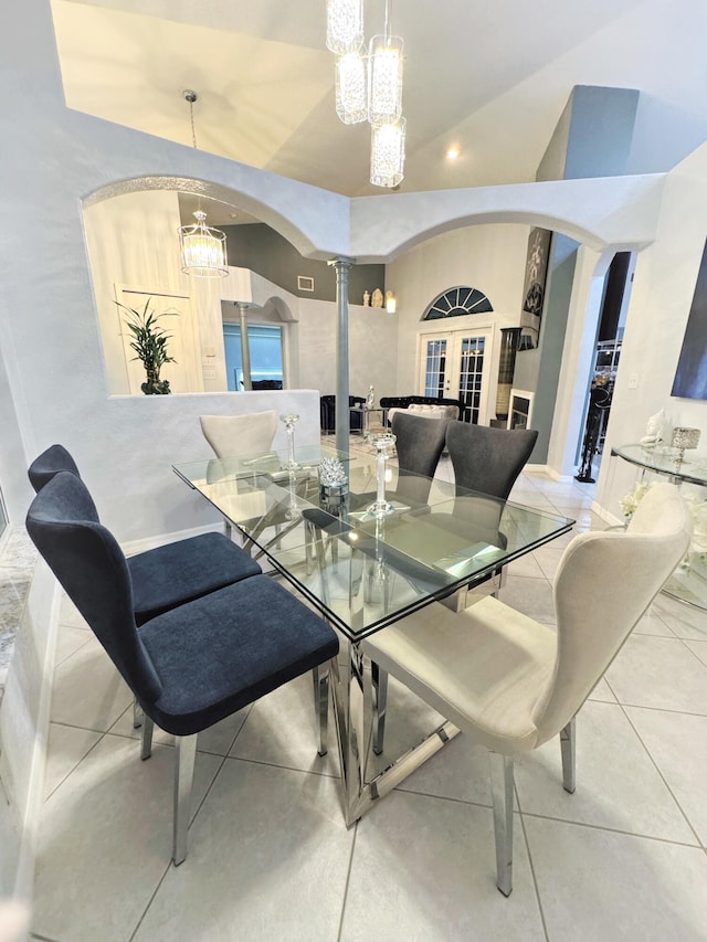 dining room with french doors, an inviting chandelier, light tile patterned flooring, and ornate columns