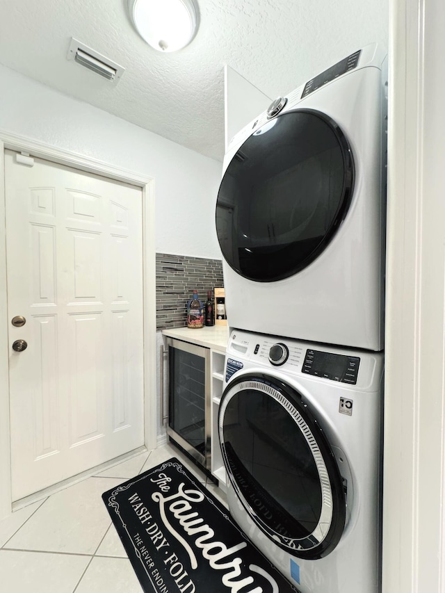 laundry room featuring stacked washer / dryer and light tile patterned flooring