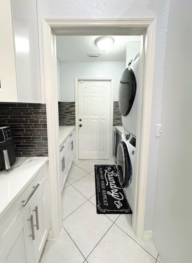 clothes washing area featuring stacked washer / drying machine and light tile patterned floors