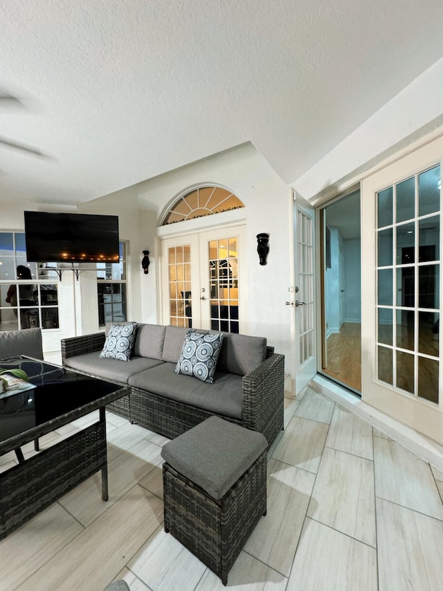 living room with ceiling fan, wood-type flooring, french doors, and a textured ceiling