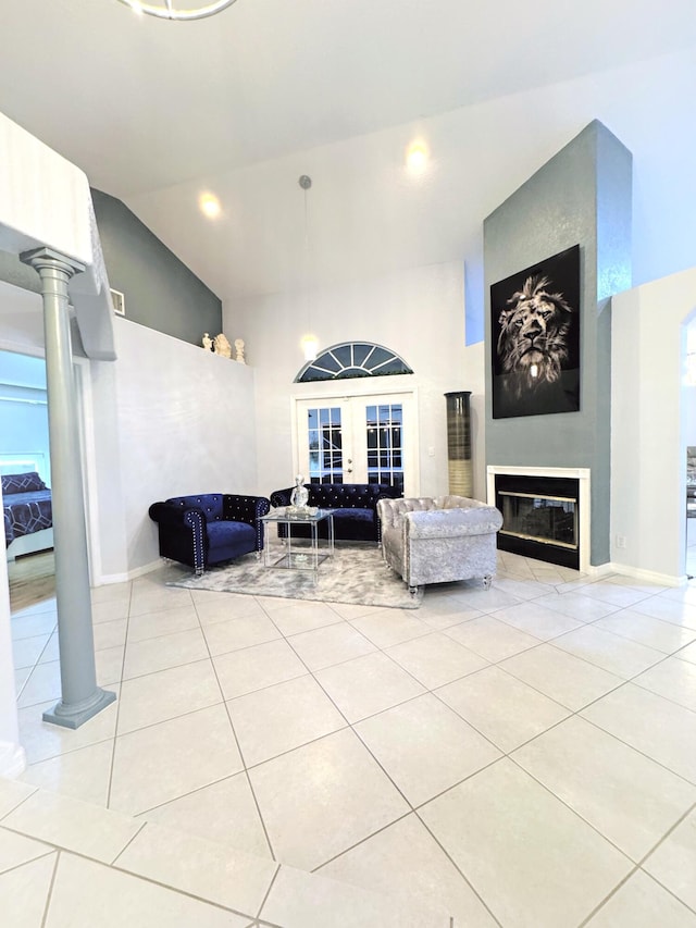 living room with a large fireplace, french doors, decorative columns, light tile patterned floors, and vaulted ceiling