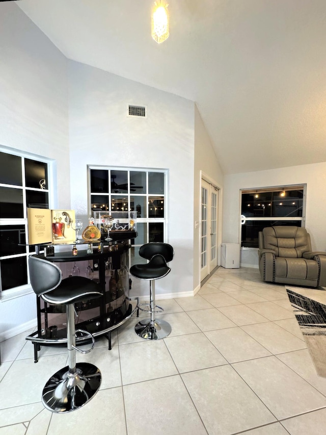 tiled dining space featuring high vaulted ceiling and french doors