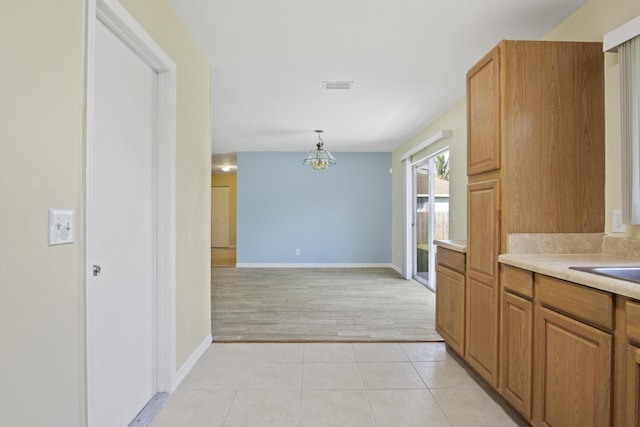 kitchen featuring pendant lighting, a notable chandelier, and light hardwood / wood-style floors