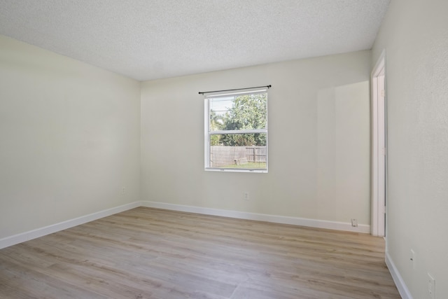 spare room featuring light wood-type flooring and a textured ceiling