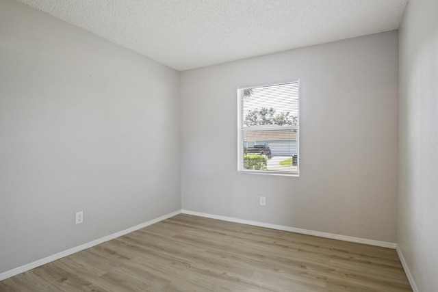 unfurnished room with a textured ceiling and light hardwood / wood-style floors