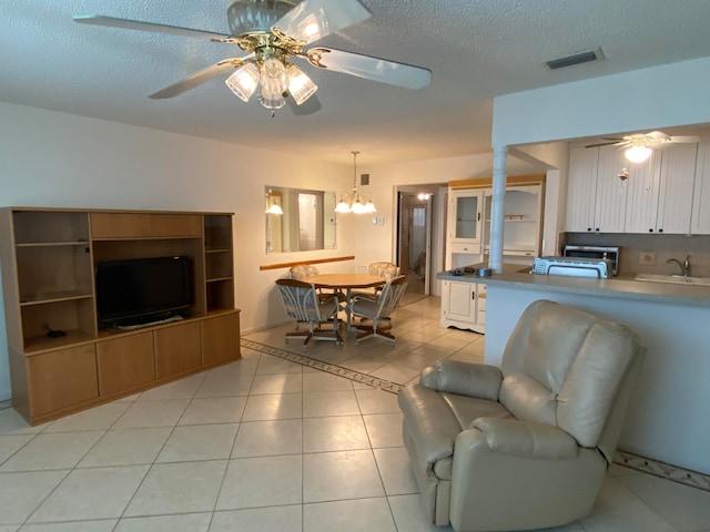 living room with a textured ceiling, ceiling fan with notable chandelier, light tile patterned floors, and sink