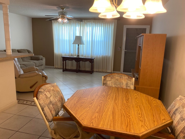 tiled dining space featuring ceiling fan, a textured ceiling, and decorative columns