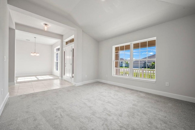 carpeted empty room featuring lofted ceiling and a notable chandelier