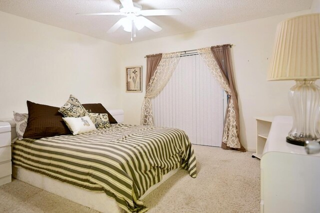 carpeted bedroom with ceiling fan and a textured ceiling