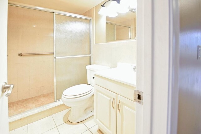 bathroom with tile patterned flooring, toilet, walk in shower, and vanity