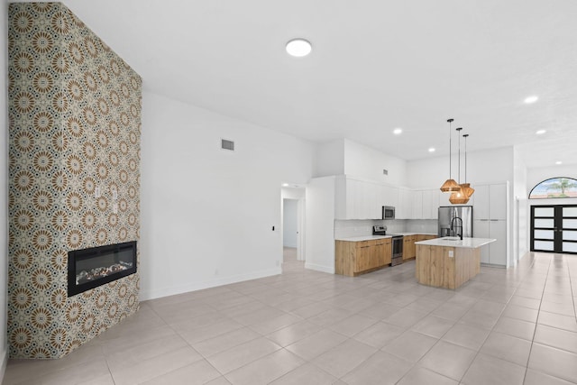 kitchen featuring open floor plan, appliances with stainless steel finishes, light countertops, and a glass covered fireplace