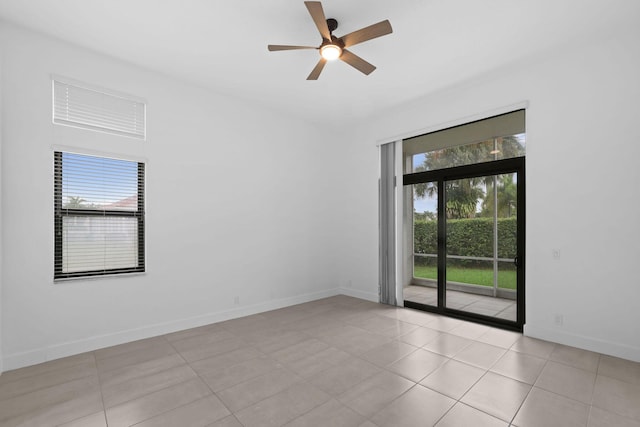 tiled empty room featuring plenty of natural light and baseboards