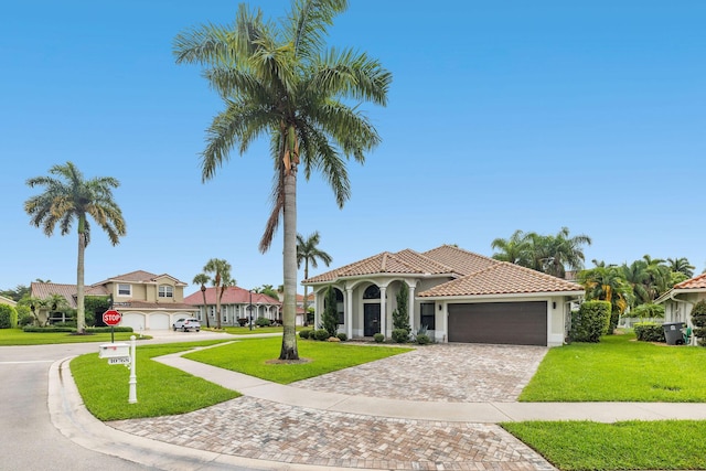 mediterranean / spanish-style house featuring an attached garage, a tiled roof, decorative driveway, and a front yard