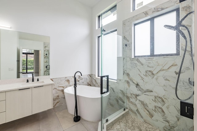 full bathroom featuring a freestanding tub, a marble finish shower, vanity, and tile walls