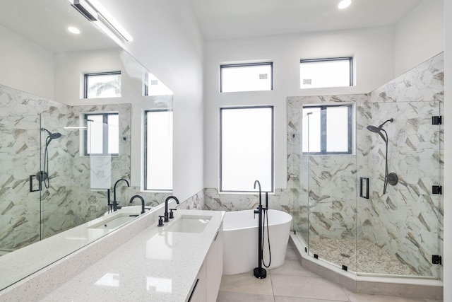 bathroom featuring a healthy amount of sunlight, a soaking tub, a marble finish shower, and vanity