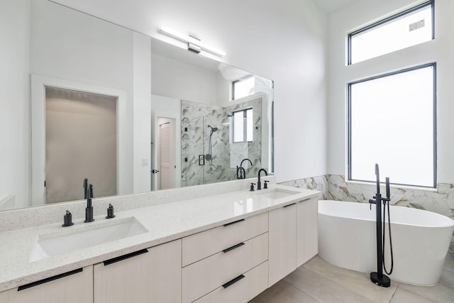 full bathroom featuring a wealth of natural light, a marble finish shower, and a sink