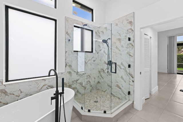 full bathroom with a closet, tile patterned flooring, a freestanding tub, and a marble finish shower