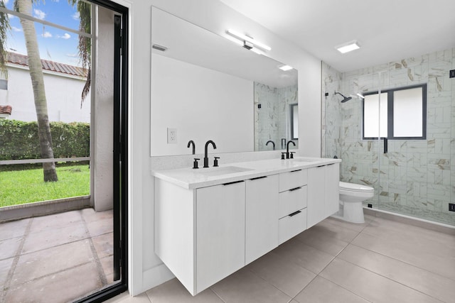 bathroom with a marble finish shower, double vanity, a sink, and toilet