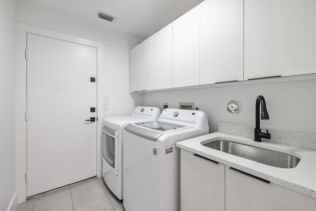 laundry area featuring sink, light tile patterned flooring, washing machine and clothes dryer, and cabinets