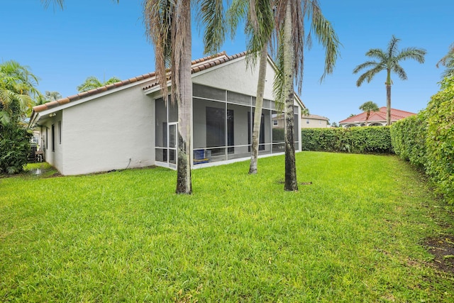 back of house with a sunroom, a fenced backyard, a lawn, and stucco siding