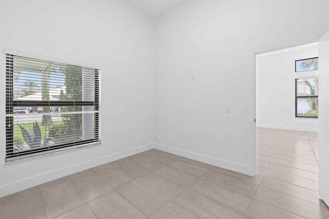 empty room featuring light tile patterned flooring and baseboards