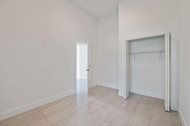 unfurnished bedroom featuring a closet, a high ceiling, and light tile patterned floors