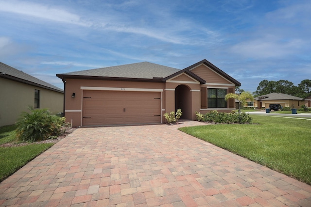 single story home with decorative driveway, a garage, a front yard, and stucco siding