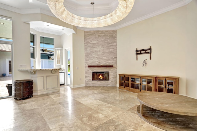 living room featuring a stone fireplace, a high ceiling, a tray ceiling, light tile patterned floors, and crown molding