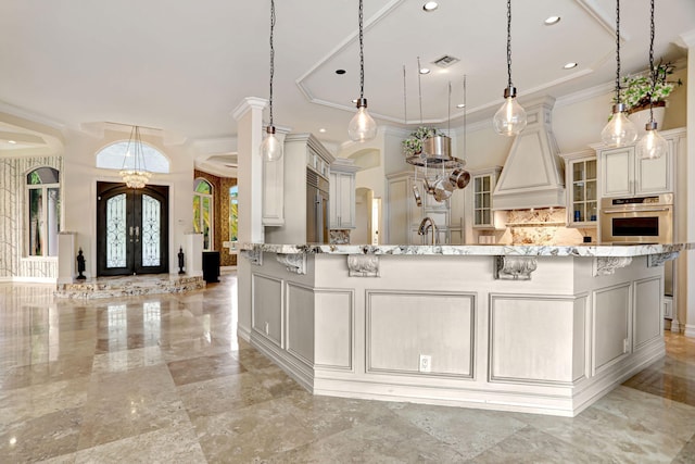 kitchen with decorative light fixtures, oven, french doors, light tile patterned floors, and custom exhaust hood