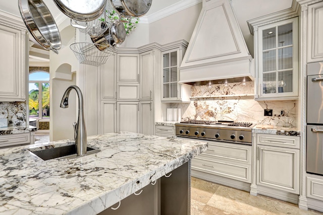 kitchen with backsplash, premium range hood, stainless steel gas cooktop, sink, and light tile patterned floors