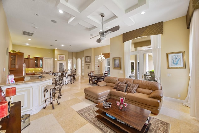 living room with coffered ceiling, beamed ceiling, ceiling fan with notable chandelier, and a high ceiling