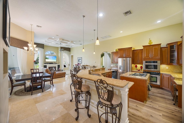 kitchen with a kitchen breakfast bar, backsplash, stainless steel appliances, a large island, and a chandelier