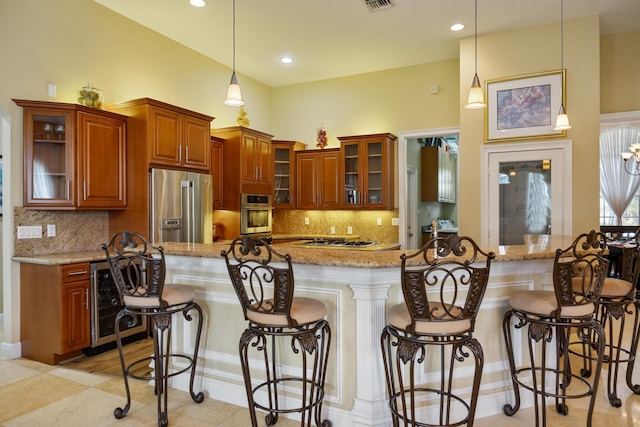 kitchen featuring hanging light fixtures, beverage cooler, stainless steel appliances, a kitchen breakfast bar, and light stone countertops