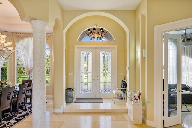 foyer entrance featuring a chandelier, french doors, and ornate columns