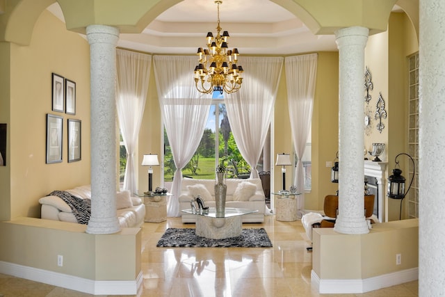 living room featuring a raised ceiling, decorative columns, and an inviting chandelier