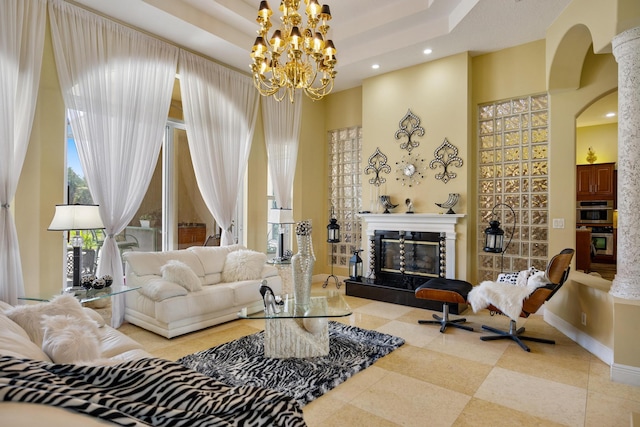 living room featuring a high ceiling, a tray ceiling, a premium fireplace, and a notable chandelier