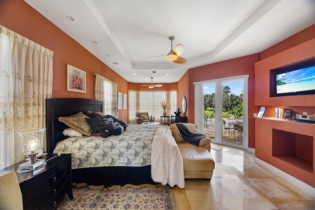 bedroom featuring access to outside, ceiling fan, french doors, a textured ceiling, and a tray ceiling