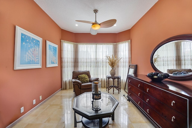 living area with ceiling fan, a textured ceiling, and a healthy amount of sunlight