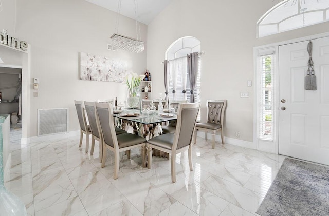 dining area featuring a towering ceiling and a chandelier