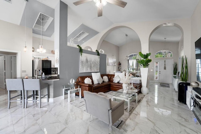 living room featuring a high ceiling and ceiling fan with notable chandelier