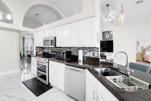 kitchen with white cabinets, hanging light fixtures, dark stone countertops, appliances with stainless steel finishes, and tasteful backsplash