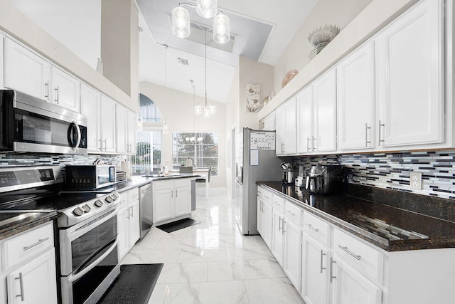 kitchen with decorative backsplash, pendant lighting, white cabinets, and stainless steel appliances