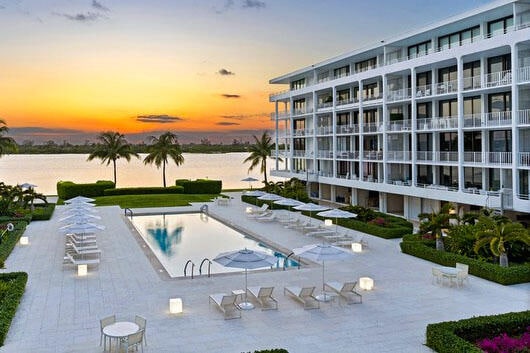 pool at dusk with a patio and a water view