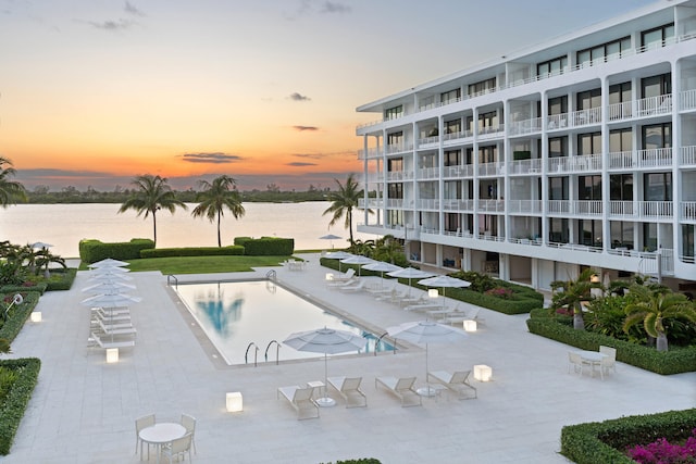 pool at dusk with a patio and a water view