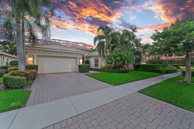 mediterranean / spanish home with a lawn and a garage